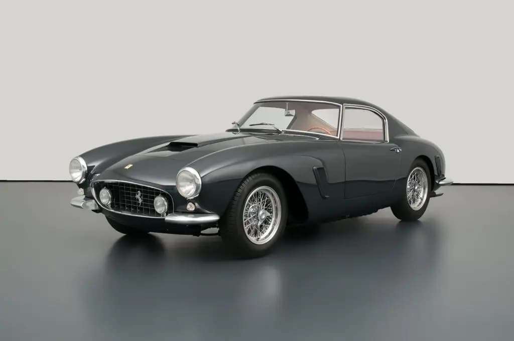 A classic black Ferrari 250 GT Berlinetta on display in a minimalistic setting with a neutral background.