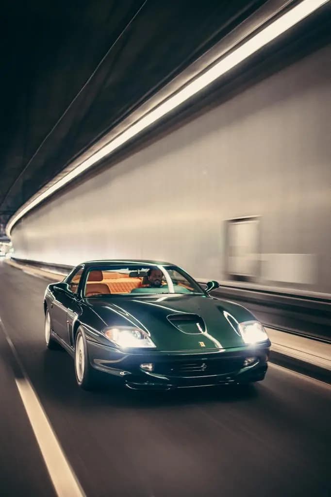 A dark green Ferrari speeding through a tunnel with motion blur, highlighting the car's sleek design and powerful presence.